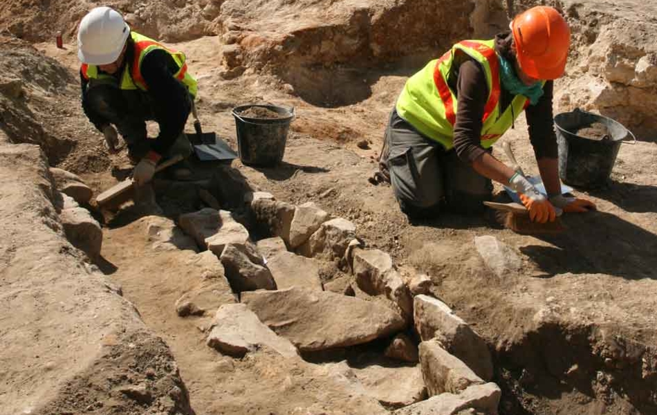 Des archéologues dégagent une tombe à coffrage en dalles de grès. L'architecture funéraire caractérise souvent des pratiques propres à chaque époque.