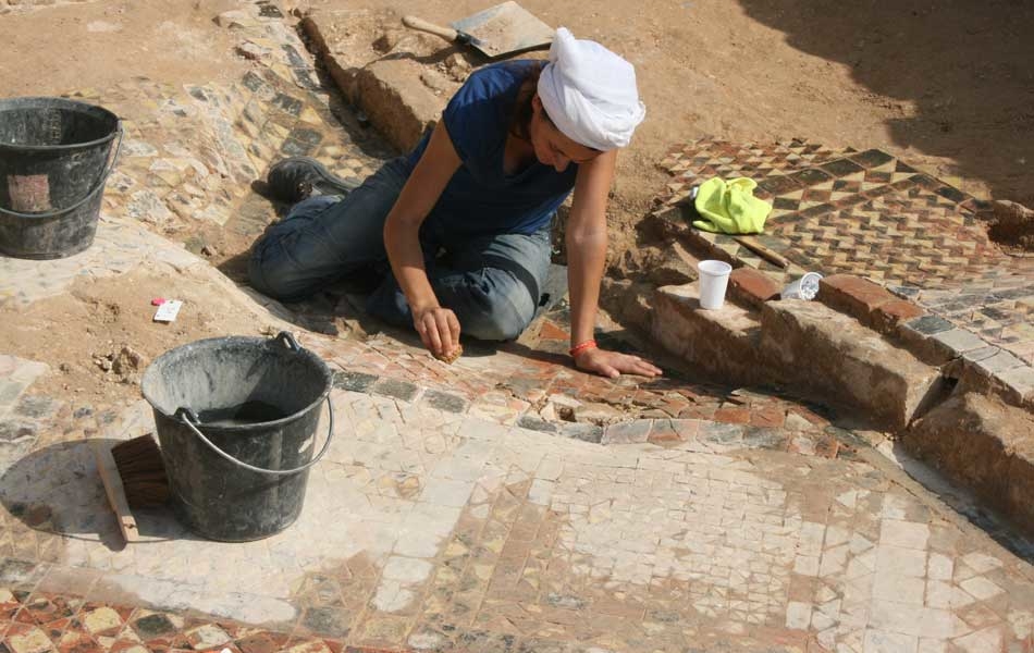 Une archéologue nettoie les pavages de la crypte principale à l'eau déminéralisée.