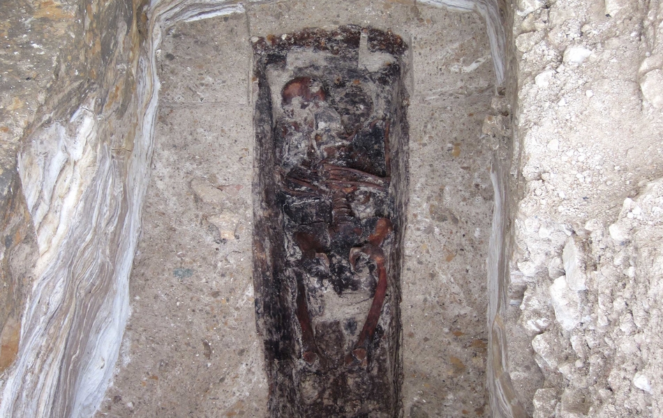 Le couvercle en bois du cercueil s’est décomposé et les fragments se sont mêlés aux restes osseux.
