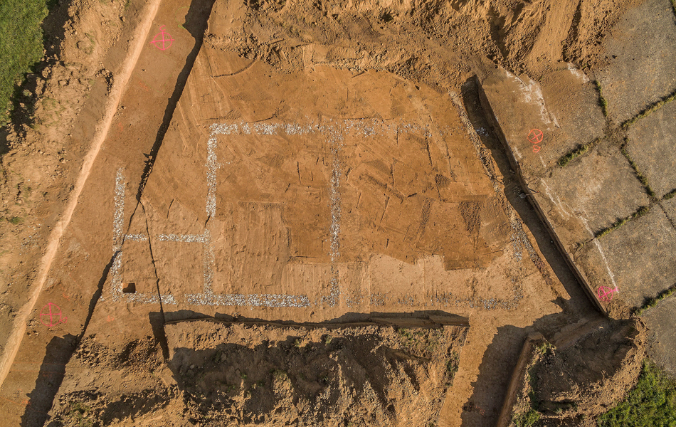 Photo aérienne des vestiges des fondations d’un édifice suggérant 4 espaces rectangulaires. 