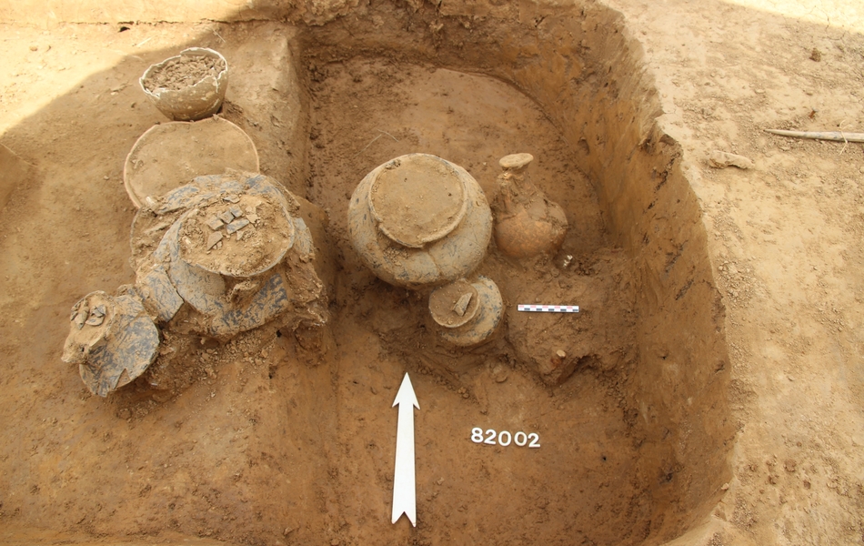 Photo de deux urnes cinéraires et d’offrandes sur deux niveaux d’une même fosse funéraire.