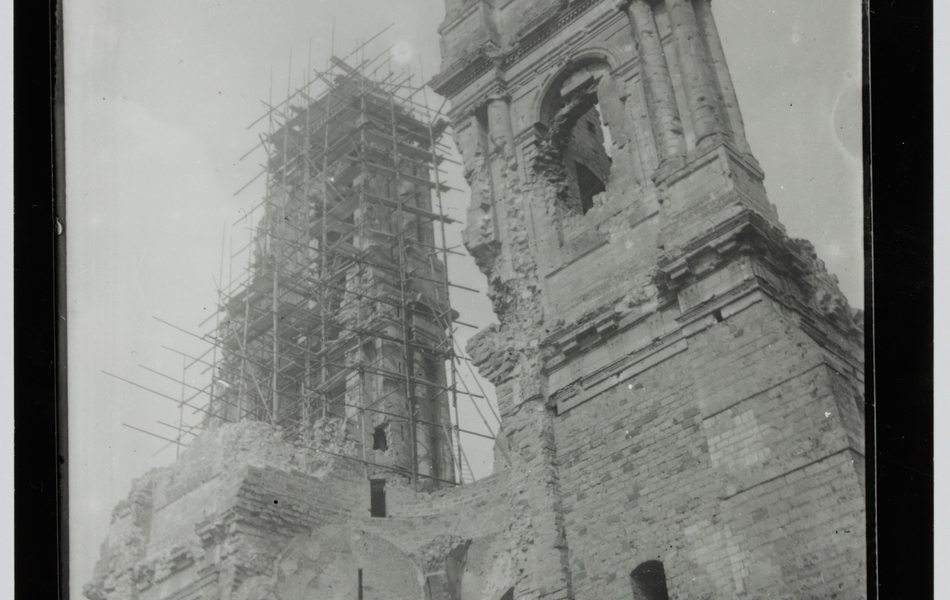Photographie noir et blanc montrant les ruines de tours contre lesquelles on a monté un échafaudage.