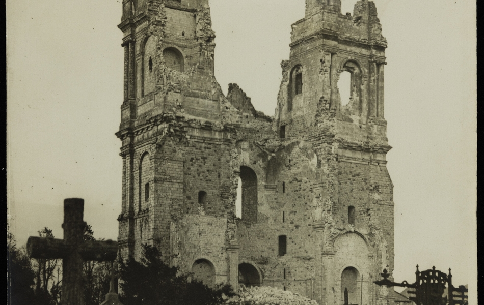 Photographie noir et blanc montrant un cimetière dominé par les ruines de deux tours.